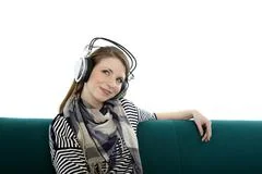 Beautiful Young Smiling Woman Sitting On A Sofa And Listens To Music With Hea