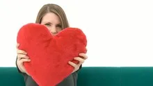Woman cuddling with a heart pillow