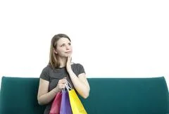 Portrait Of Young Contemplative Woman Sitting On A Sofa With Shopping Bags
