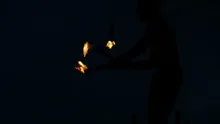 Slowmotion fire sticks juggler performing
